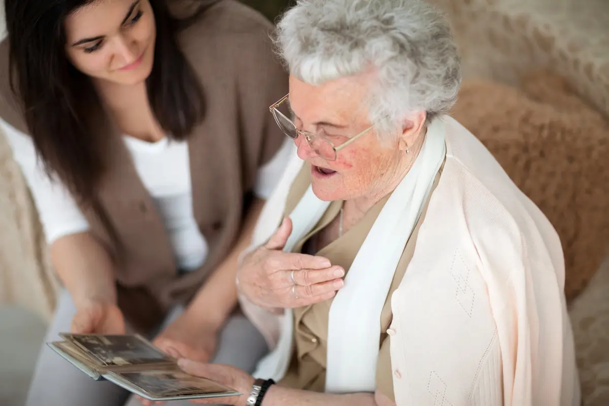 Moving from Assisted Living to Memory Care Guide Grandmother and grandchild looking through a photo album, reflecting moving from assisted living to memory care and the emotional transition families navigate