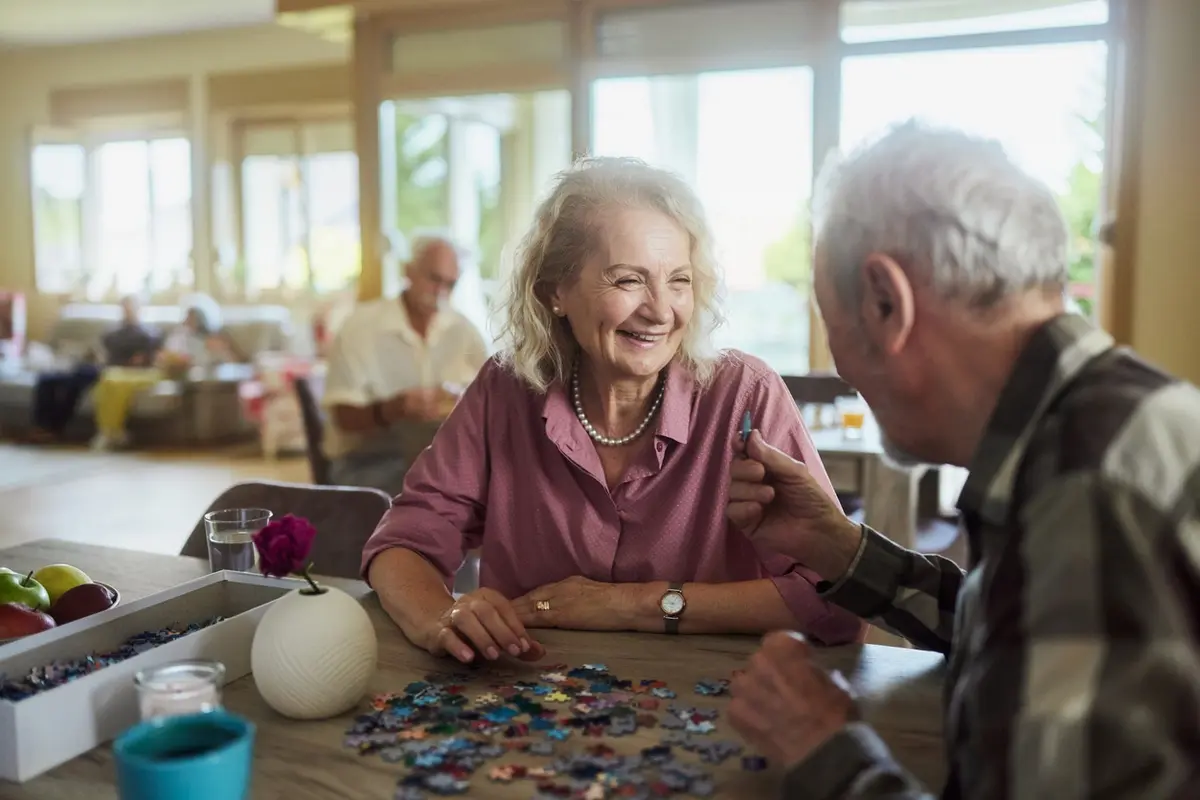 Benefits of Puzzles for Seniors: older adults smile while working on a jigsaw puzzle